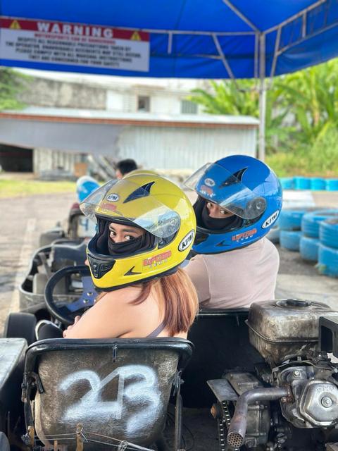 Rica Mae and Mark Lino looking back from their go-karts in yellow and blue helmets